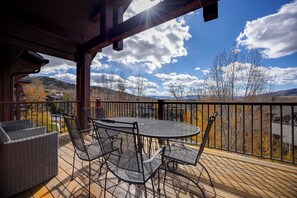 A wooden deck with a round table and chairs, overlooking a mountainous landscape. - EL5303 | Mtn Getaway | Resort Amenities | 2 King Suites | Air Chilling (Steamboat Springs)
