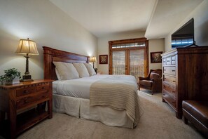 A bedroom with a large bed, wooden headboard, bedside tables, a dresser, and a television. - EL5303 | Mtn Getaway | Resort Amenities | 2 King Suites | Air Chilling (Steamboat Springs)