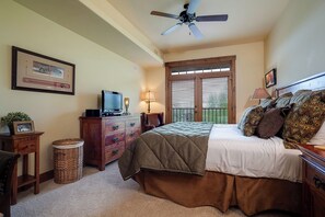 Ein Schlafzimmer mit Bett, Kommode, Fernseher und Deckenventilator.