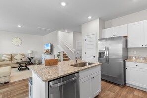 A modern kitchen with white cabinets, stainless steel appliances, and a granite countertop. - Coastal Clubhouse | Beach + Golf + Putting green (North Myrtle Beach)