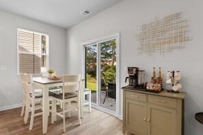 A dining area with a table and chairs, a coffee machine, and a cabinet with kitchenware. - Coastal Clubhouse | Beach + Golf + Putting green (North Myrtle Beach)
