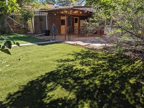 A patio area with a brick building, outdoor seating, and a well-maintained lawn. - Charming 3BR/2BA Craftsman near Hospitals - Yard & BBQ (Pueblo)