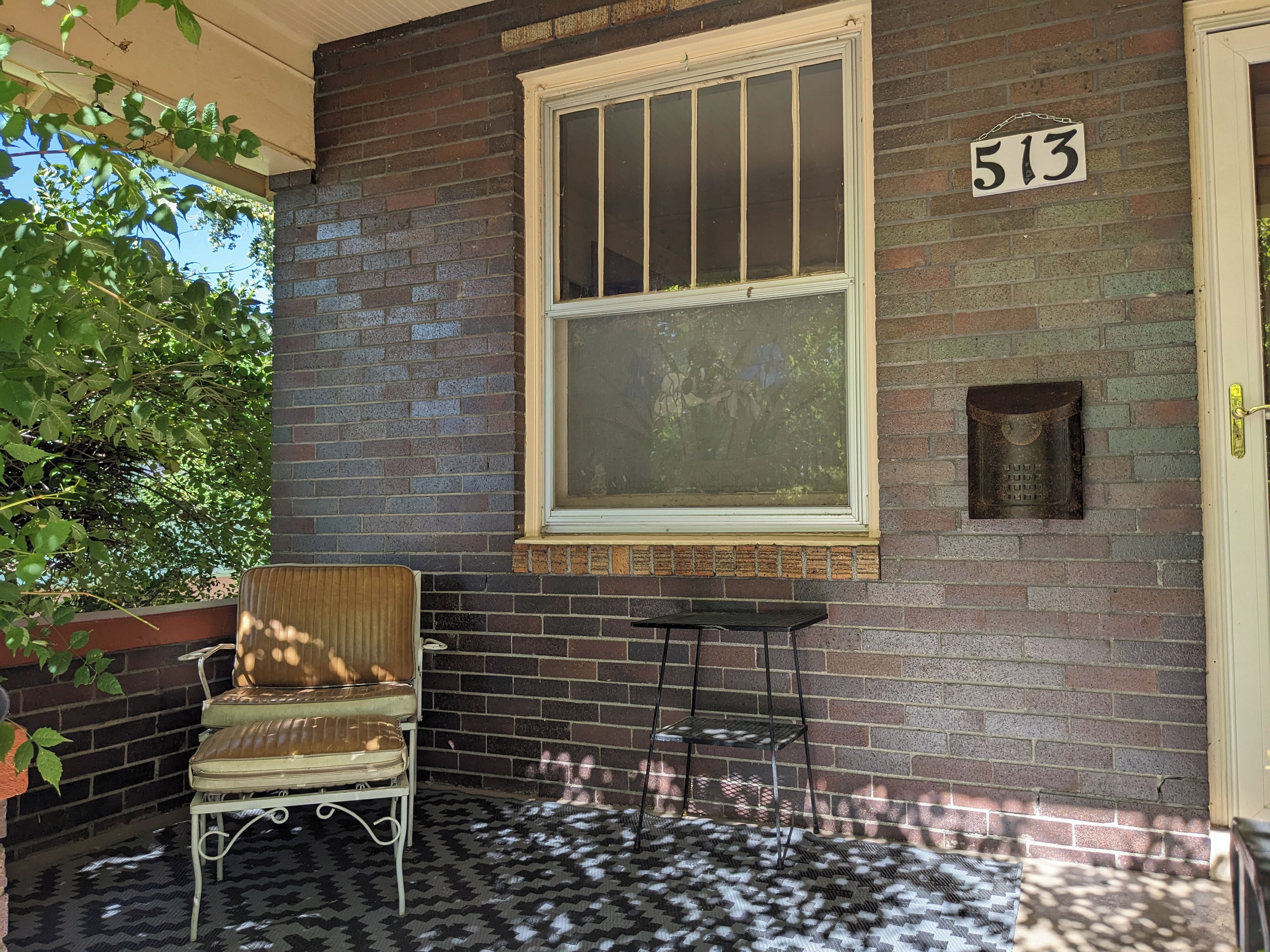 A brick exterior with a window, a door, and a number sign.