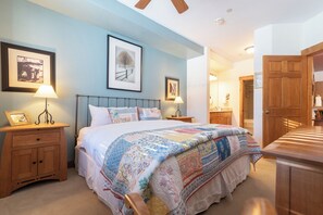 A bedroom with a large bed, two bedside tables with lamps, a wooden wardrobe, and a door leading to a bathroom. - TL2102 | Warm and Cozy Home | Close to Skiing | 10 Hot Tubs | Winter Shuttle (Steamboat Springs)
