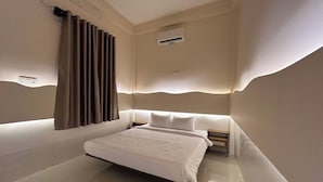 Une chambre moderne avec un lit, une table de chevet, un climatiseur fixé au mur et un rideau.