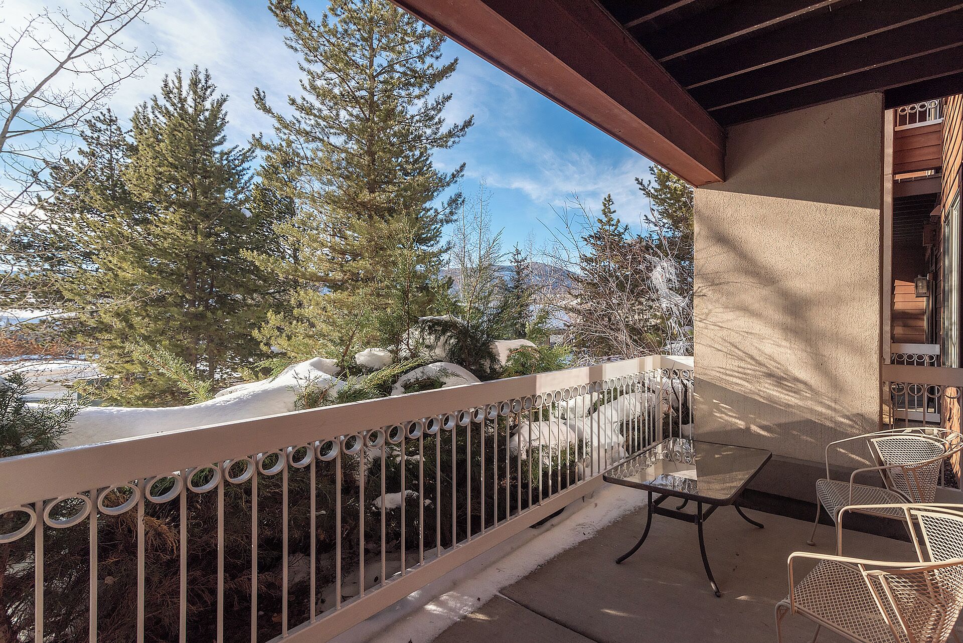 A balcony with a metal railing, a table, and chairs.