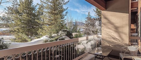 A balcony with a metal railing, a table, and chairs.