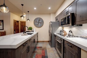 A modern kitchen with a large island, dark wooden cabinets, stainless steel appliances, and pendant lighting. - TL2103 | Easy Access to Slopes | Beautiful Décor | Winter Shuttle | Hot Tubs (Steamboat Springs)