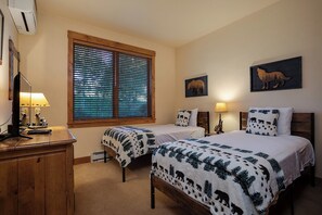 Une chambre d’hôtel avec deux lits, un bureau avec une lampe, une fenêtre avec des stores et des œuvres d’art murales.