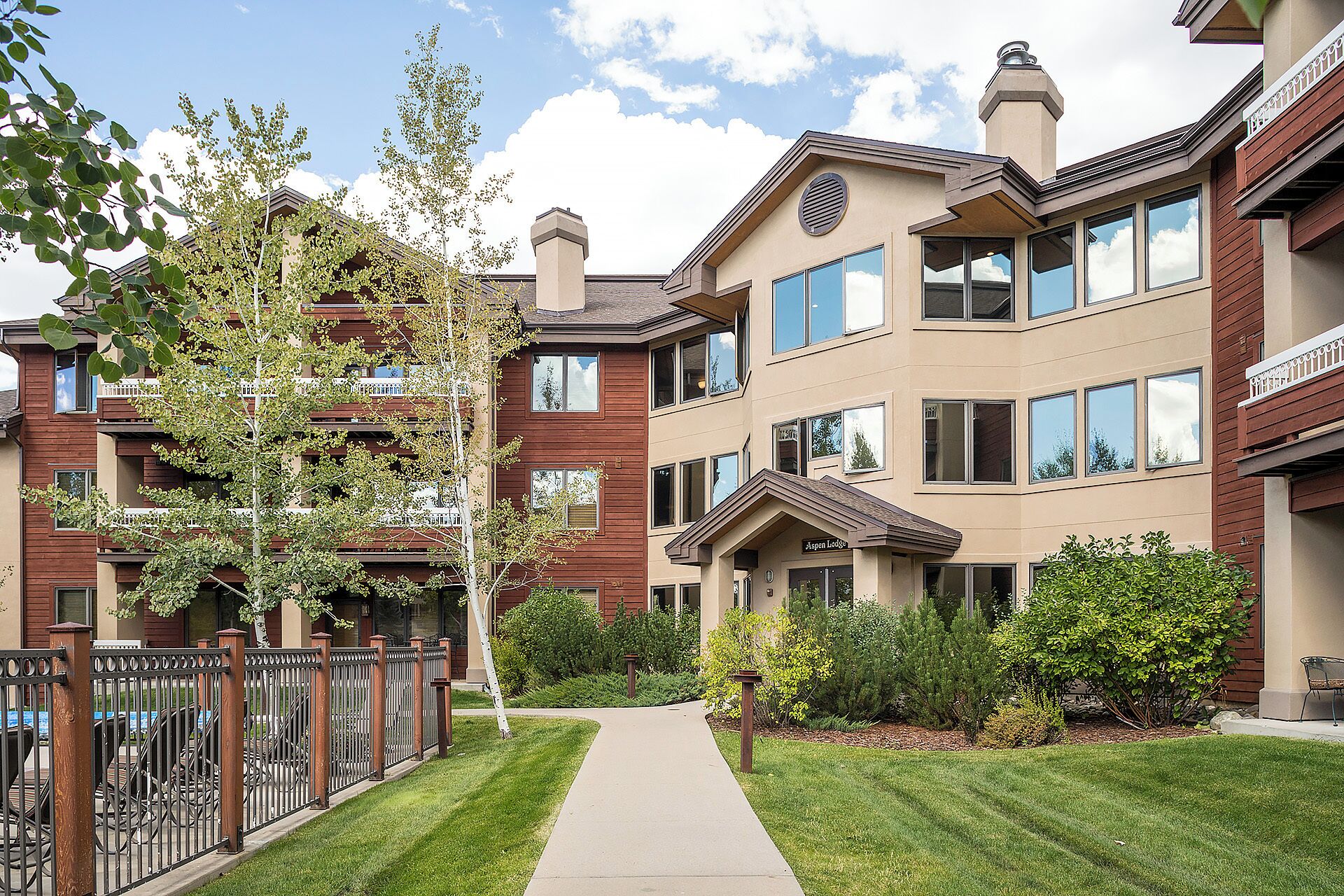 A multi-story residential building with a central entrance, a covered porch, and a well-maintained lawn.