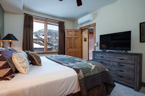 A bedroom with a bed, a dresser, a television, and a window with a view of a snowy landscape. - TL2109 | Perfect for a Couple or Small Family | A/C | Great Amenities (Steamboat Springs)