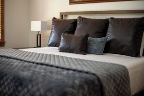 Ein ordentlich bezogenes Bett mit einer gesteppten Decke, einem Kopfteil und mehreren Kissen.