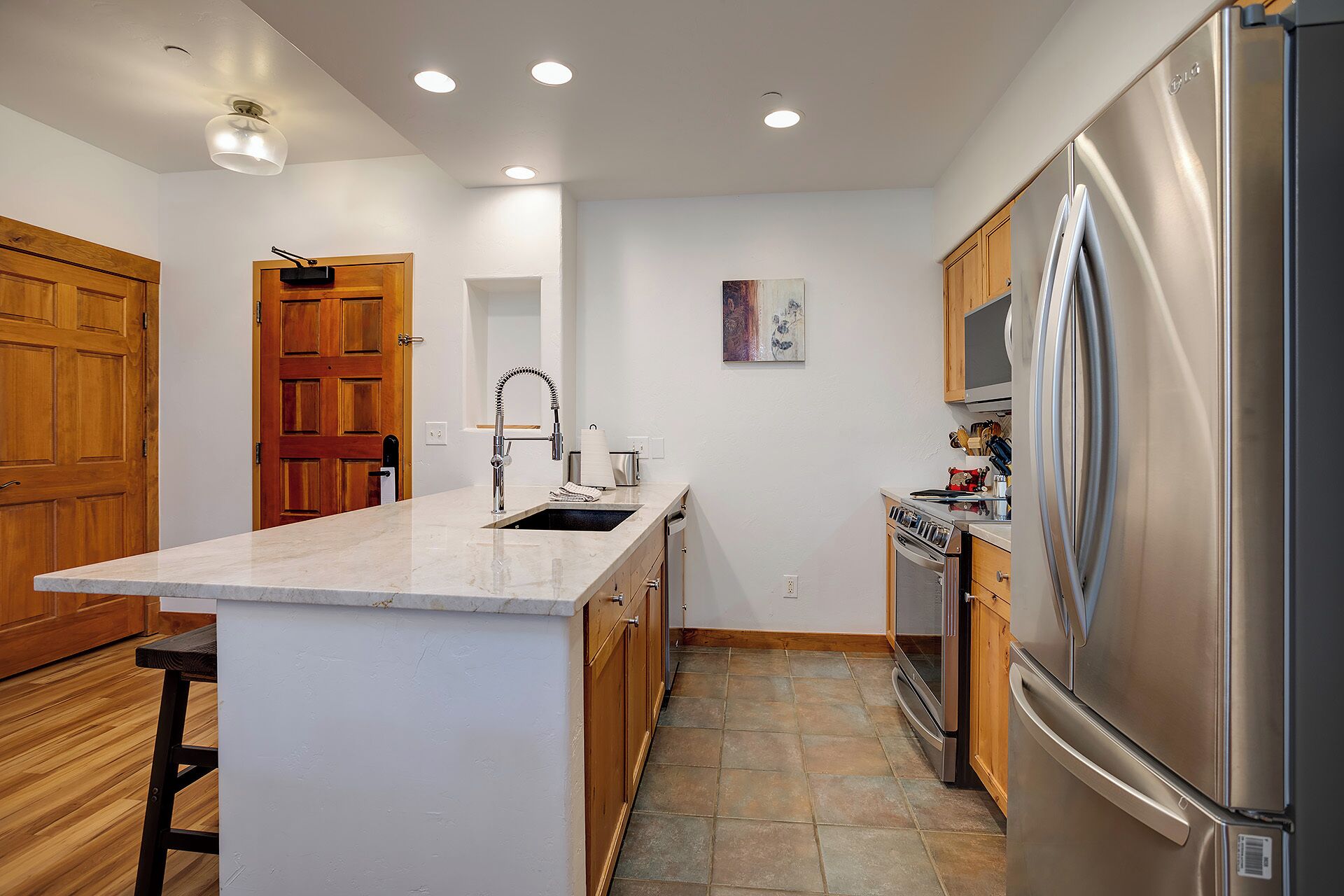 Una cocina moderna con una isla central, electrodomésticos de acero inoxidable y armarios de madera.