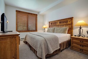 A bedroom with a wooden headboard, two bedside lamps, a TV on a wooden dresser, and a window with blinds. - TL2205 | Beautifully Appointed Vacation Home | Close to Skiing | A/C (Steamboat Springs)