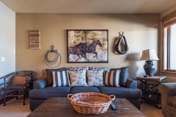 A living room with a sofa, a coffee table, a basket, a painting, a lamp, and a chair. - TL2210 | Perfect for a Couple | Winter Specials | Winter Shuttle | 10 Hot Tubs (Steamboat Springs)