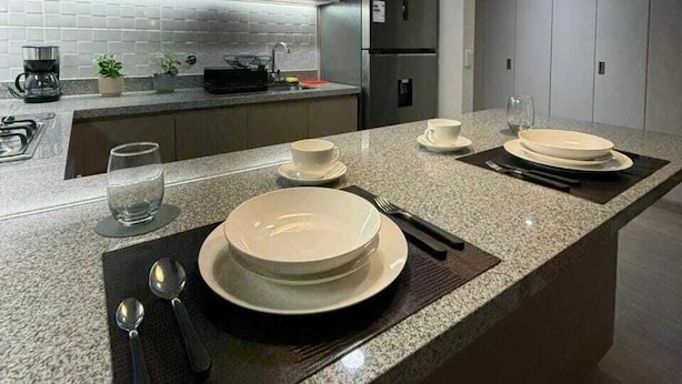 Eine moderne Küche mit Granit Arbeitsplatten, Edelstahlgeräten und Pendelleuchten.