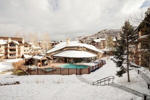 Ein Resort mit Pool, umgeben von Schnee, Holzhäusern und einer Bergkulisse.