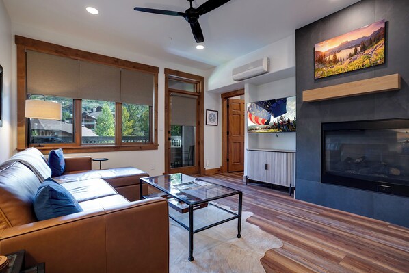 A modern living room with a leather sofa, a glass coffee table, and a fireplace. - TL2211 | Mountain Condo | Close to Skiing | A/C | 10 Hot Tubs (Steamboat Springs)