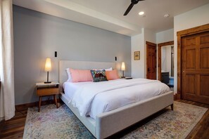 A bedroom with a large bed, two bedside tables, a ceiling fan, and a wooden door. - TL2211 | Mountain Condo | Close to Skiing | A/C | 10 Hot Tubs (Steamboat Springs)