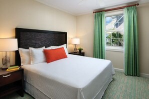 A hotel room with a large bed, two bedside tables, a window with curtains, and a view of the outside.