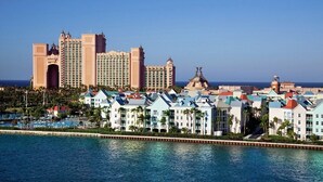 A resort with multiple buildings, a water body in the foreground, and a clear sky. - Cozy 1-BR Villa in fantastic Harborside at Atlantis in Paradise Island (Paradise Island)