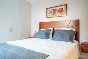 Ein Schlafzimmer mit einem Bett, zwei Nachttischen, einem Beistelltisch und einem Gemälde an der Wand.