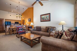 A spacious living room with a brown leather sofa, a wooden coffee table, and a dining area with wooden chairs and a table. - TL2301 | Great Location | Top Floor | Beautiful Décor | Winter Shuttle (Steamboat Springs)