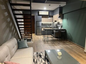 A modern living room with a sofa, a glass coffee table, and a kitchen area with a dining set. - Modern Duplex with Terrace | Alcanfores (Miraflores)