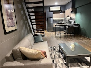 A modern living room with a sofa, a glass coffee table, and a staircase leading to an upper level. - Modern Duplex with Terrace | Alcanfores (Miraflores)