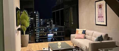A modern living room with a dining area, a city view, and a staircase.