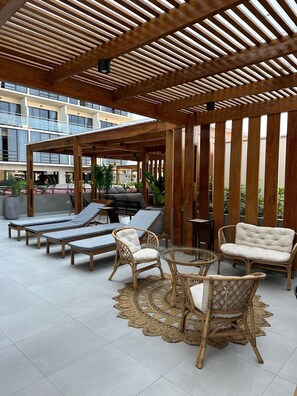 An outdoor lounge area with wooden pergolas, lounge chairs, and a round table. - Elegant Duplex with Terrace Sea View (Miraflores)