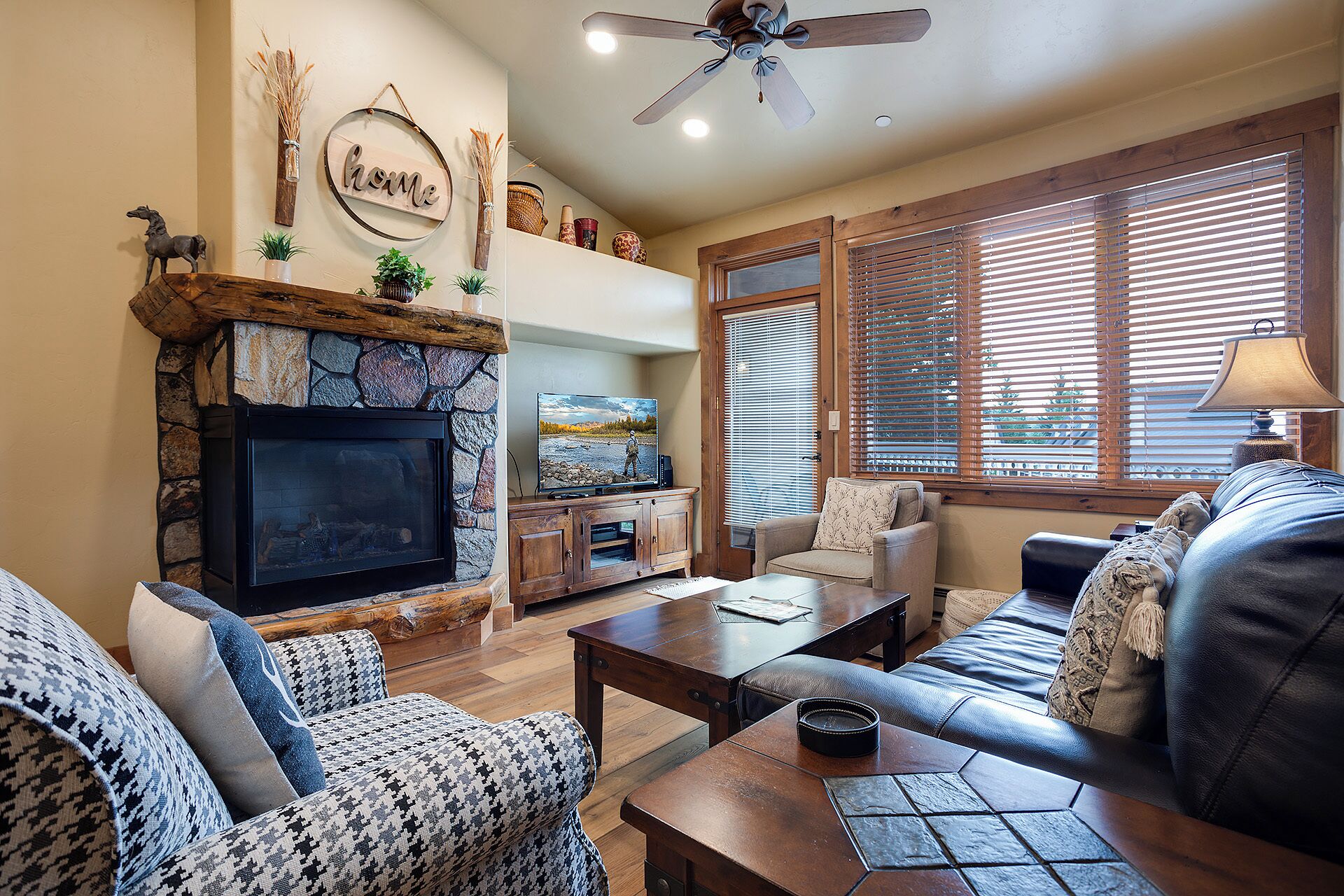 A living room with a stone fireplace, a television, a sofa, and a coffee table.