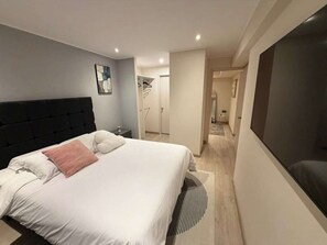 A modern bedroom with a large bed, a flat-screen TV, and a walk-in closet. - Boutique 2BR in Miraflores | Pool · Gym · BBQ (Miraflores)
