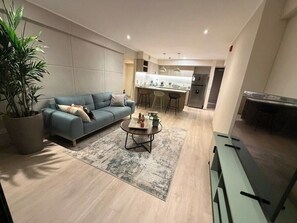 A modern living room with a sofa, a coffee table, and a potted plant. - Boutique 2BR in Miraflores | Pool · Gym · BBQ (Miraflores)