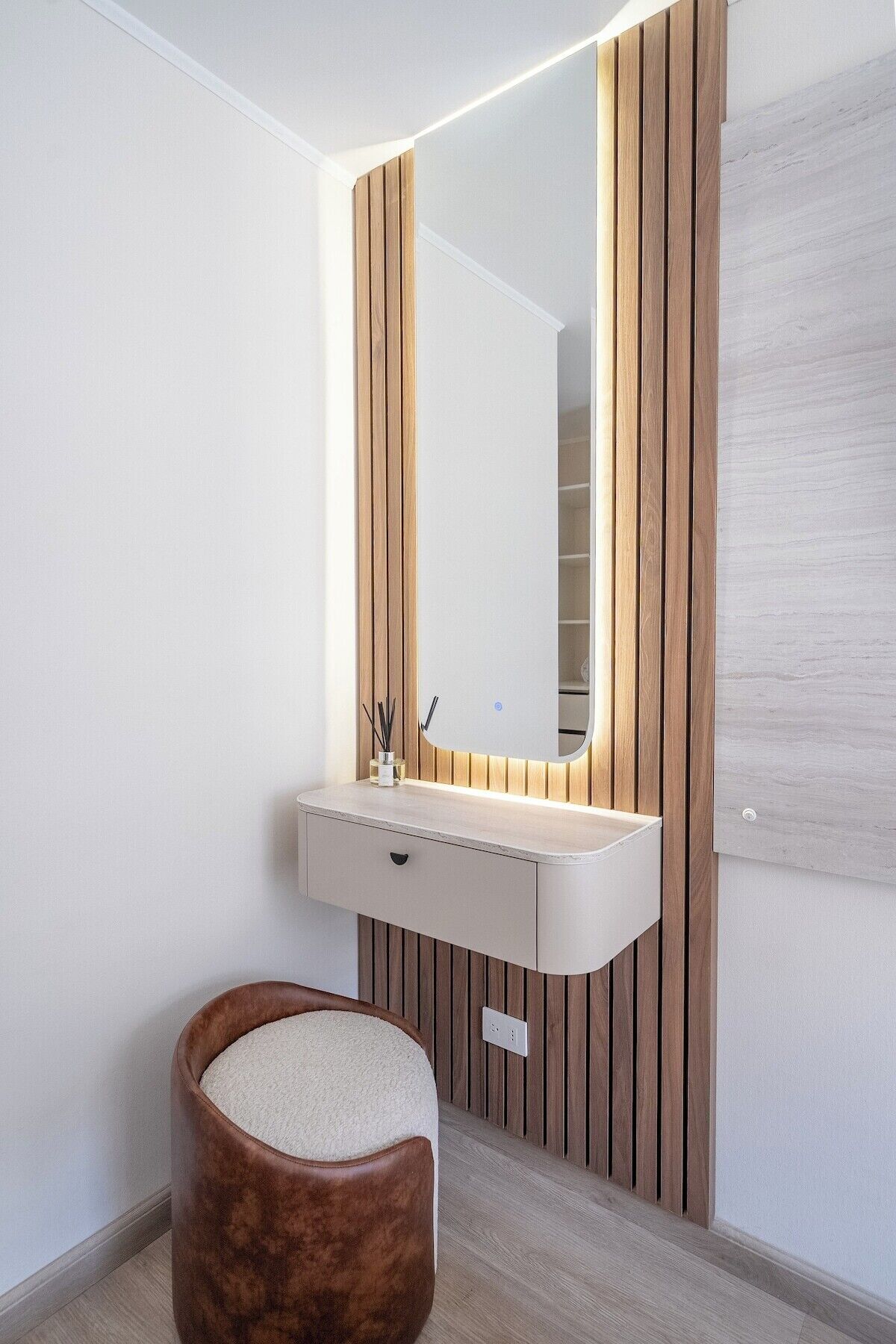 A modern bathroom with a vanity, mirror, and wooden panel wall.