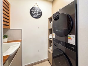 Et lille vaskerum med en vægmonteret tørretumbler, en lille vask og en hylde med toiletartikler.