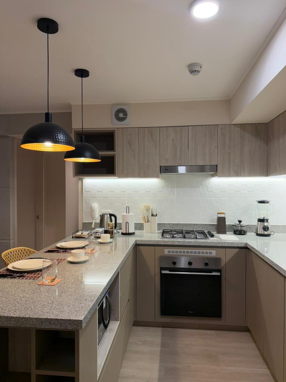 A modern kitchen with a central island, stainless steel appliances, and pendant lighting.
