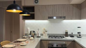 A modern kitchen with a central island, stainless steel appliances, and pendant lighting.