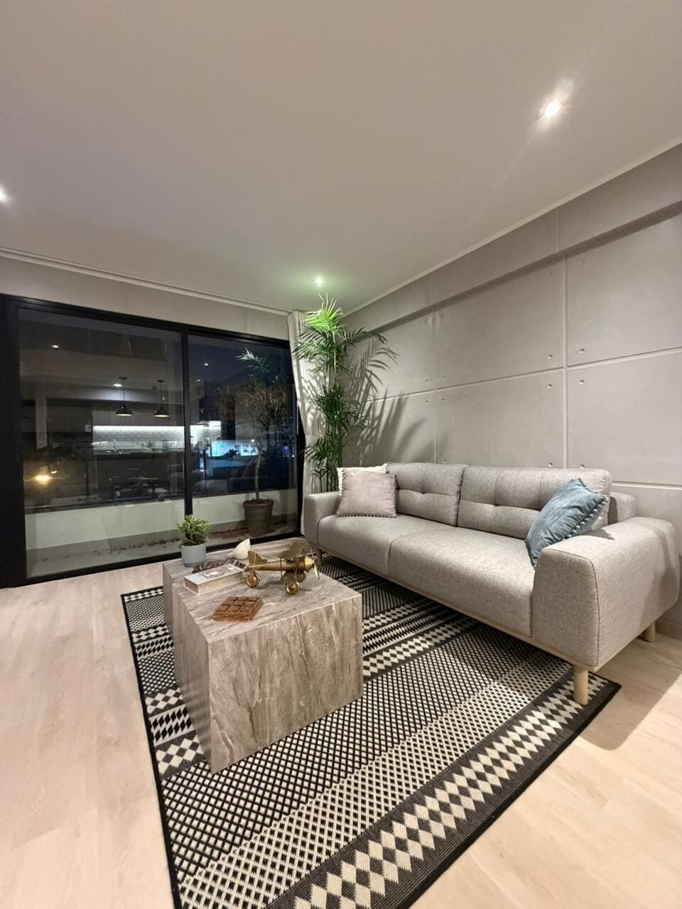 A modern living room with a sofa, a coffee table, and a patterned rug.