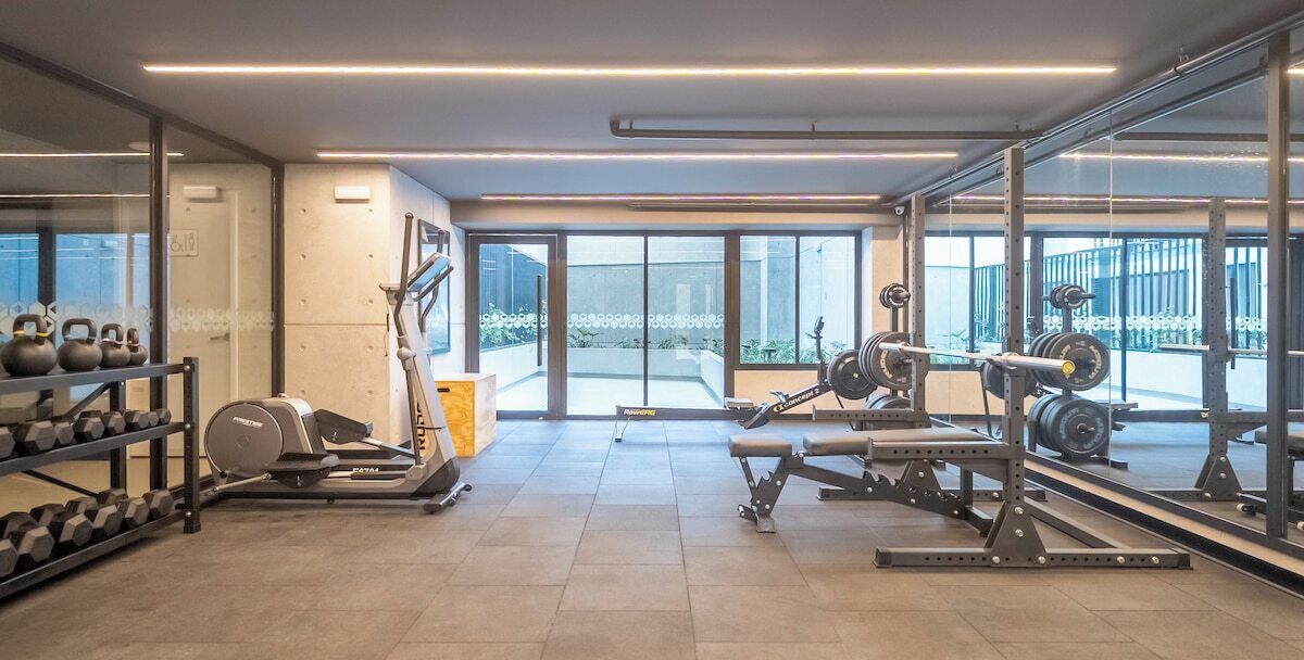 A gym with weightlifting equipment, treadmills, and dumbbells.