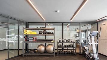 A gym with exercise equipment, including kettlebells, dumbbells, and a treadmill.