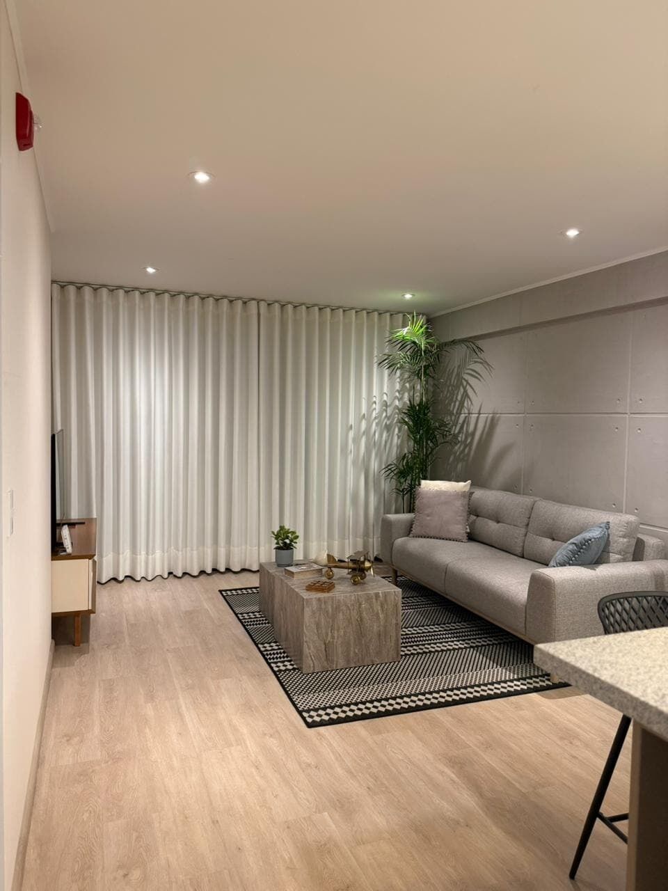 A modern living room with a sofa, a coffee table, and a dining area.