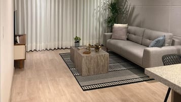 A modern living room with a sofa, a coffee table, and a dining area.