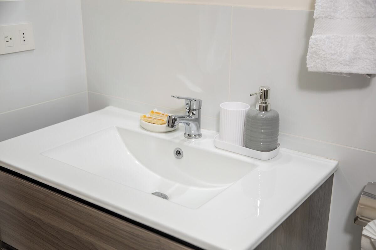 Ein modernes Badezimmer mit einem weißen Waschbecken, einer Seifenspender und einem Handtuchhalter.