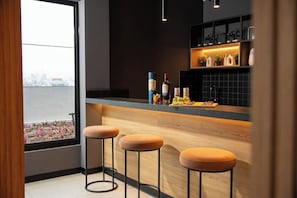 A modern kitchen with a bar area, stools, and a view of the city. - Miraflores Boutique Escape | Pool · Rooftop · Gym (Miraflores)