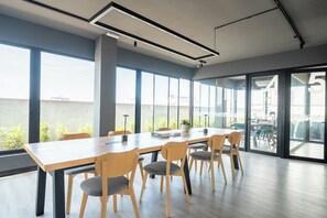A modern conference room with a long table and chairs, large windows, and a view of the outside. - Miraflores Boutique Escape | Pool · Rooftop · Gym (Miraflores)