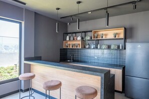 A modern kitchen with a central island, bar stools, and a built-in refrigerator. - Miraflores Boutique Escape | Pool · Rooftop · Gym (Miraflores)