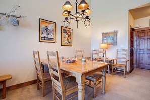 Un comedor con mesa y sillas de madera, un candelabro y carteles en la pared.