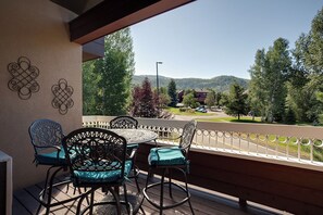 Un balcón con una mesa redonda y cuatro sillas, con vista a una zona residencial con casas y árboles.
