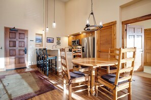 A dining area with a wooden table and chairs, a kitchen with stainless steel appliances, and a wooden door. - TL2305 | Vaulted Ceiling | A/C | 10 Hot Tubs | 4 Pools | Close to Mtn (Steamboat Springs)